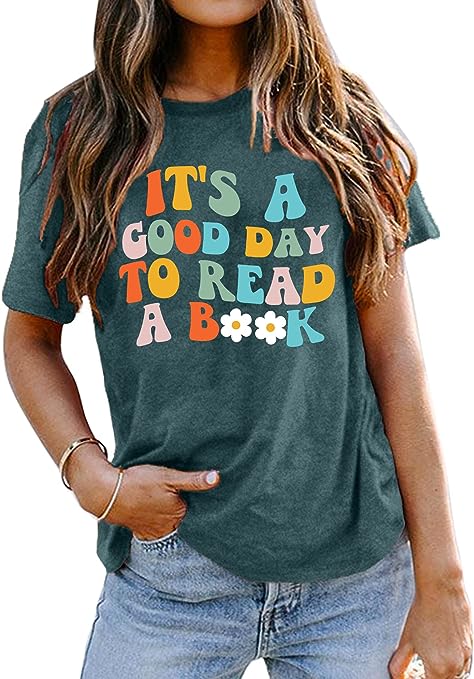 A woman wearing a shirt that says IT IS A GOOD DAY TO READ A BOOK.